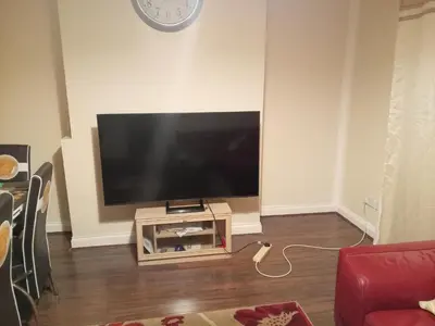 a flat screen tv on a stand in a living room at Kaffuhsmartt in Drumchapel