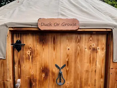 a wooden door with a sign that reads puck or groove at Bracken Barns Glamping & Massage in Minishant