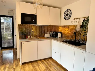 a kitchen with white cabinets and a clock on the wall at Scotney Retreat in Moffat