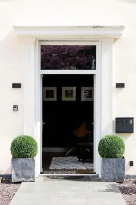 a front door of a white house with two bushes at 2 Bedroom in the Heart of Loch Lomond in Balloch