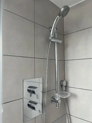 a shower with a shower head in a bathroom at Lovely spacious home near station in Moffat