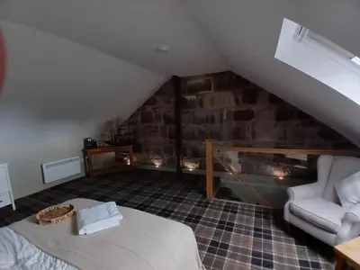 a bedroom with a bed and a couch in a attic at Castle View 3 bedroom with garden in Dumbarton