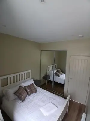 a bedroom with a large white bed and a mirror at Castle View 3 bedroom with garden in Dumbarton