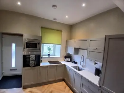 a large kitchen with white cabinets and a window at Castle View 3 bedroom with garden in Dumbarton