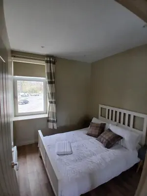 a bedroom with a white bed with a window at Castle View 3 bedroom with garden in Dumbarton