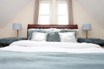 a bedroom with a bed with white sheets and pillows at Greenknowes Entire Private Estate in Kelty