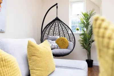a swing chair in a living room with yellow pillows at Greenknowes Entire Private Estate in Kelty