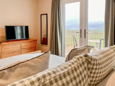 a bedroom with a bed and a tv and a balcony at Ardvenhor in Gartocharn