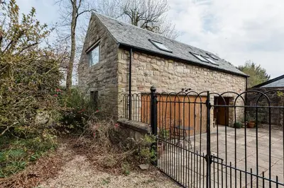 a stone building with a gate and a fence at Converted Historical Stone Coach House in Glasgow