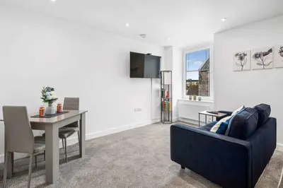 a living room with a blue couch and a table at Modern & Central 1BR Flat with Sky TV in Oban
