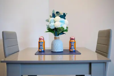 a table with a vase of flowers and two cans of peanuts at Modern & Central 1BR Flat with Sky TV in Oban