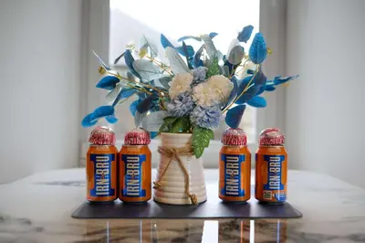 a table with four bottles of honey and a vase with flowers at Modern & Bright 2BR Flat - Short Walk to Town in Oban