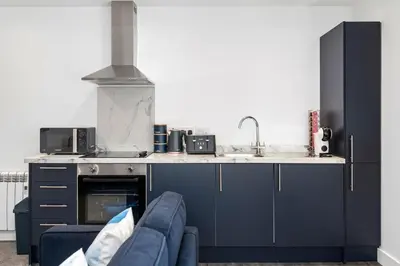 a kitchen with blue cabinets and a blue couch at Modern & Bright 2BR Flat - Short Walk to Town in Oban