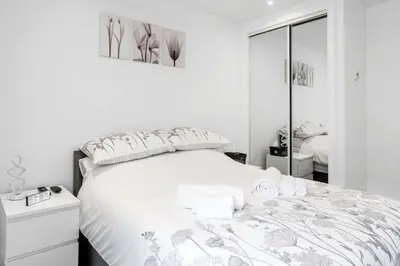 a white bedroom with a bed and a mirror at Modern & Bright 2BR Flat - Short Walk to Town in Oban