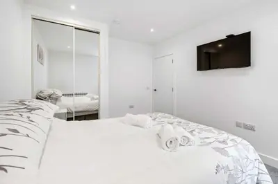 a white bedroom with a bed and a mirror at Modern & Bright 2BR Flat - Short Walk to Town in Oban