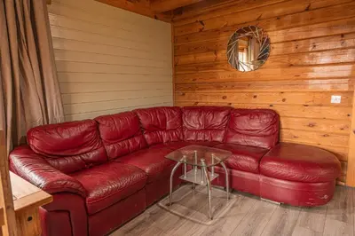 a red leather couch in a room with a table at Lodge 2 in Stirling