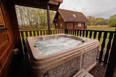 a hot tub on a deck with a house at Lodge 3 in Stirling