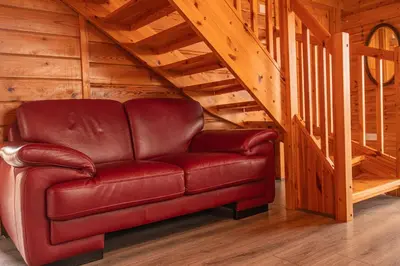 a red leather couch in a room with stairs at Lodge 3 in Stirling