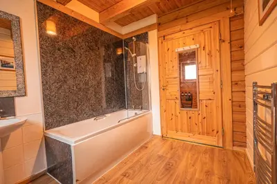 a bathroom with a tub and a wooden floor at Lodge 5 in Stirling