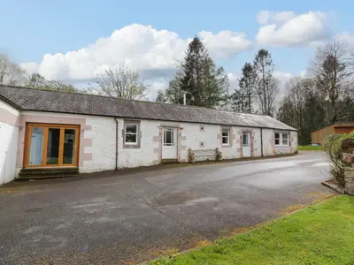 an old white building with a parking lot at The Stables in Thornhill
