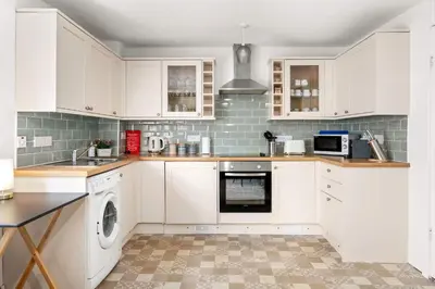 a kitchen with white cabinets and a dishwasher at Modern 1BR Apartment - Close to ferry terminal with free parking in Oban