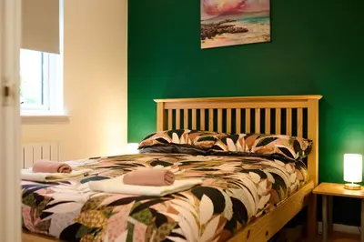 a bedroom with a bed with a green wall at Modern 1BR Apartment - Close to ferry terminal with free parking in Oban