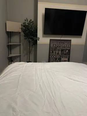 a bedroom with a white bed with a flat screen tv at Cozy Central 1 Min to Tube in Moffat