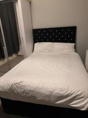 a white bed with a black headboard in a bedroom at Cozy Central 1 Min to Tube in Moffat