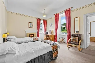 a bedroom with two beds and a chair at Rosemount in Campbeltown