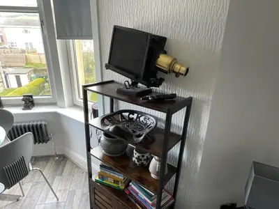 a television on a stand in a room with a window at Isle of Bute Blissful Retreat- Stunning 3 Bed Flat in Rothesay