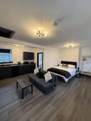 a bedroom with a bed and a couch and a bed and a tv at GlasVenn Cottages in Irvine