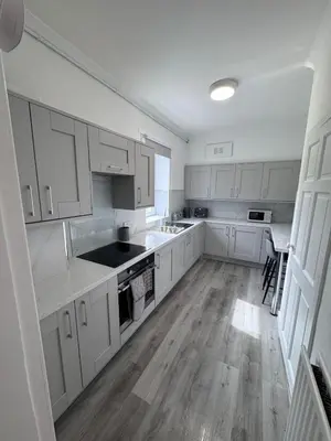 a kitchen with white cabinets and a wooden floor at Helensburgh Central Apartment - Macaulay Letting in Helensburgh