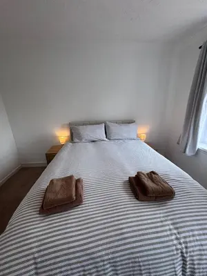 a large white bed with two brown towels on it at Helensburgh Central Apartment - Macaulay Letting in Helensburgh