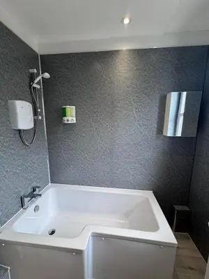 a white bath tub in a bathroom with gray walls at Helensburgh Central Apartment - Macaulay Letting in Helensburgh