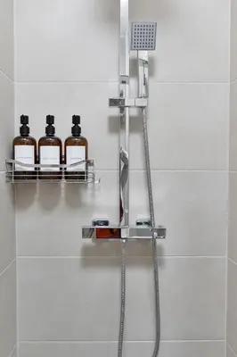 a shower with three bottles of soap on a shelf at Lovely Haymarket Apartment - Central Edinburgh in Edinburgh