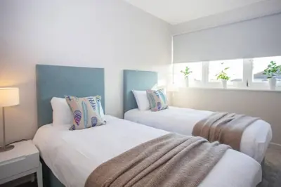 two white beds in a room with windows at Stylish 2-Bed Apartment Near Glasgow Green in Glasgow