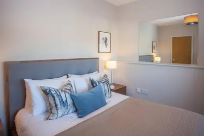 a bedroom with a bed with pillows and a mirror at Stylish 2-Bed Apartment Near Glasgow Green in Glasgow