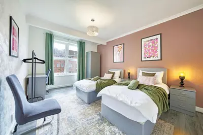 a bedroom with two beds and a chair at 2BR Shawlands Free Parking Great Location in Glasgow