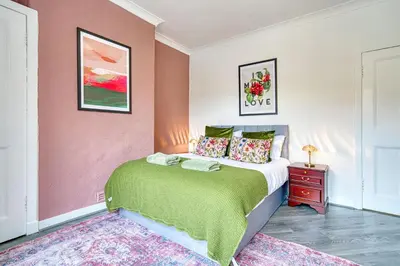 a bedroom with a bed and a pink wall at 2BR Shawlands Free Parking Great Location in Glasgow
