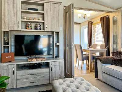 a living room with a television and a dining room at Burnside Lodge in Auchterarder
