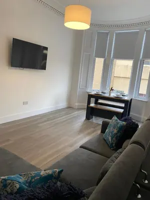 a living room with a couch and a flat screen tv at Spacious 2 bed sleeps 5 above traditional music pub in Paisley