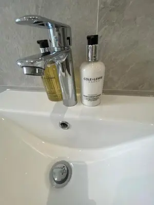 a bathroom sink with a soap dispenser and a bottle on it at Spacious 2 bed sleeps 5 above traditional music pub in Paisley
