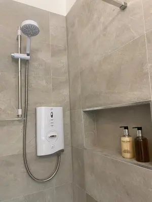 a shower with a shower head in a bathroom at Spacious 2 bed sleeps 5 above traditional music pub in Paisley