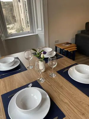 a table with plates and wine glasses on it at Spacious 2 bed sleeps 5 above traditional music pub in Paisley