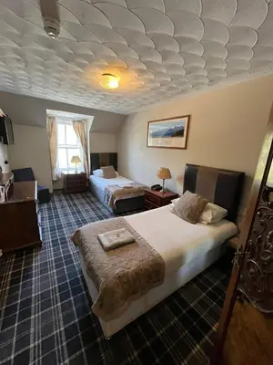 a hotel room with two beds in a room at Cairndow Stagecoach Inn in Cairndow