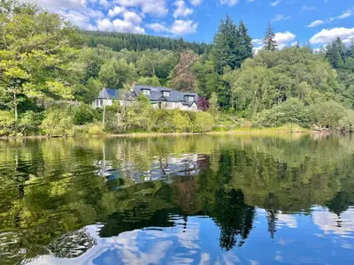 a house on the shore of a lake at Ardross Cottage in Aberfoyle