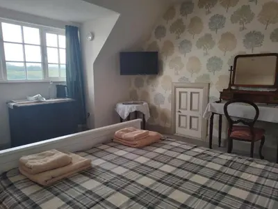 a bedroom with a bed with a mirror and a table at Ardross Cottage in Aberfoyle