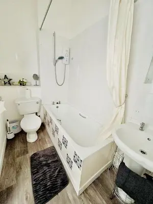 a bathroom with a tub and a toilet and a sink at Flat 156 at M Rooms in Shotts Station