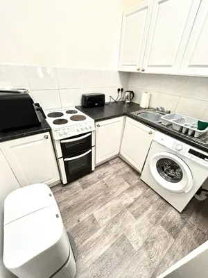 a white kitchen with a stove and a sink at Flat 156 at M Rooms in Shotts Station