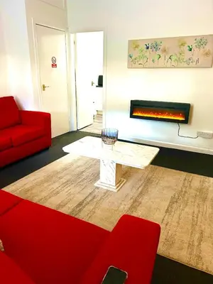 a living room with a red couch and a fireplace at Flat 156 at M Rooms in Shotts Station